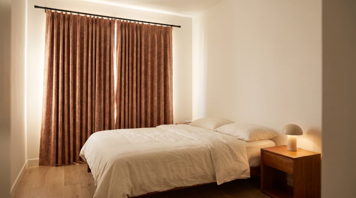 Floor-length blackout curtains on a no-drill rod in a small apartment bedroom